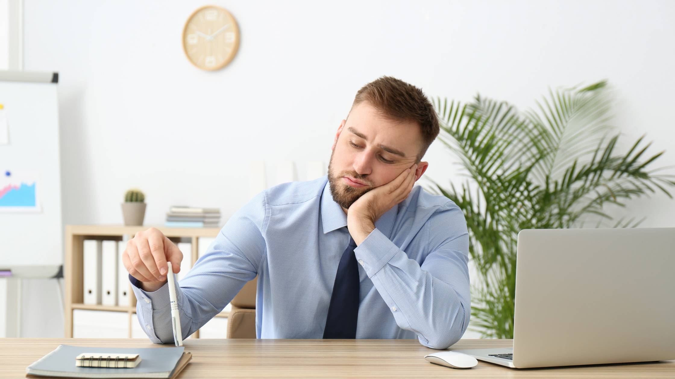 man sitting at a desk looking bored and procrastinating